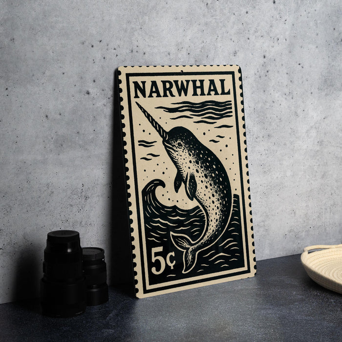 A black and white postage stamp featuring a narwhal, a type of whale, is displayed on a table.