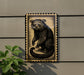a wooden frame with a black and white illustration of a cat, mounted on a wall.