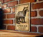 a wooden table with a framed illustration of a raccoon, which is mounted on a brick wall.