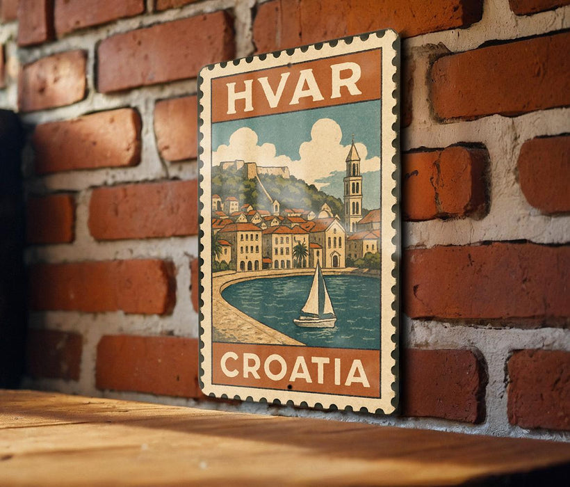 A vintage-style metal sign with the text "HVAR CROATIA" is displayed on a brick wall, featuring an illustration of a coastal town with a sailboat.