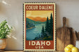 A vintage-style metal sign with a scenic illustration of a lake and mountains, along with the text "COEUR D'ALENE IDAHO USA".