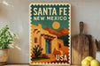 A vintage-style poster of Santa Fe, New Mexico, featuring a desert landscape with a cactus and a wooden building, is displayed on a wall next to a wooden cutting board and a potted plant.