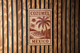 A sign with the text "COZUMEL MEXICO" is displayed on a wooden wall.