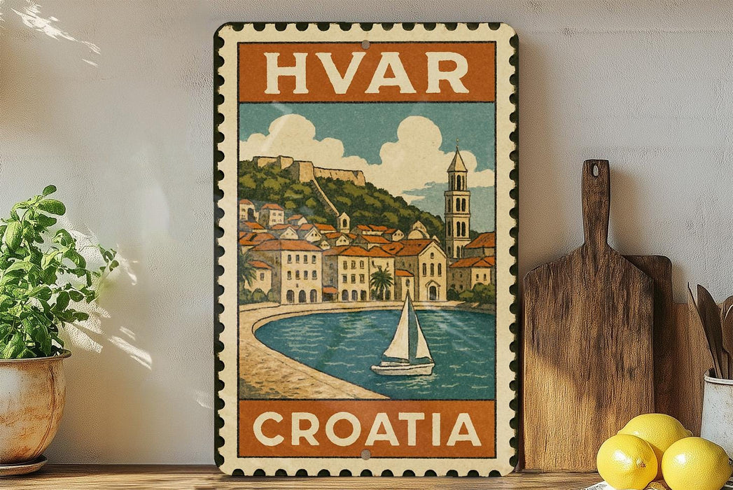 a vintage-style metal stamp with a depiction of a coastal town in Croatia, surrounded by a body of water and a sailboat. The stamp is placed on a wooden surface, with a potted plant to the left and a wooden cutting board to the right. There are also some lemons visible in the image.