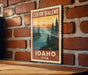 A vintage-style postage stamp depicting Coeur d'Alene, Idaho, USA, with a scenic landscape of mountains, pine trees, and a lake.