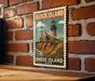 A vintage-style metal sign with a lighthouse and the text "BLOCK ISLAND RHODE ISLAND USA" is displayed on a brick wall.