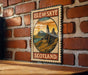 A vintage-style metal sign with the text "ISLE OF SKYE SCOTLAND" and an illustration of a mountainous landscape, mounted on a brick wall.