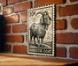a wooden table with a decorative stamp of a domestic goat on it, mounted on a brick wall.