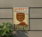 A Jersey Channel Islands postage stamp is displayed on a wall, featuring a shield with a lion and a castle, along with a depiction of boats on the water.