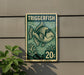 A green and white postage stamp featuring a fish illustration, mounted on a wall next to a plant.