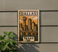 A decorative metal sign with a stylized illustration of the Dallas skyline and a bridge, mounted on a wall.