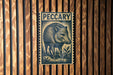 A wooden wall with a large, detailed illustration of a wild boar, which appears to be a postage stamp or a decorative piece.