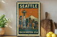 A vintage-style metal sign with the text "SEATTLE WASHINGTON USA" and an illustration of the Space Needle in Seattle, Washington.