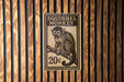 A metal sign with a squirrel monkey image and the text "SQUIRREL MONKEY" is displayed on a wooden wall.