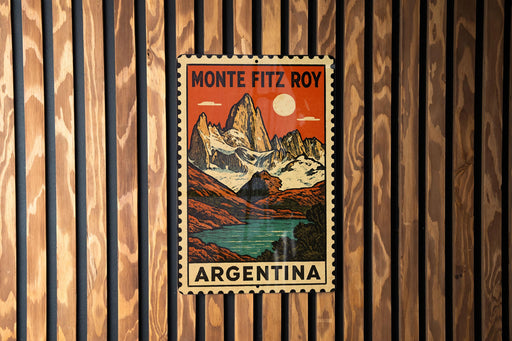A vintage postage stamp featuring a mountain landscape with a lake, mounted on a wooden wall.