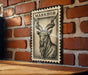 A metal stamp with a black and white illustration of a horned animal, likely a goat or ram, is mounted on a brick wall.