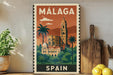 A vintage-style metal sign with the text "MALAGA SPAIN" displayed prominently, featuring an illustration of a building surrounded by palm trees and mountains.