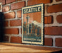 A vintage-style metal sign with the text "SEATTLE WASHINGTON USA" and an illustration of the Space Needle, mounted on a brick wall.