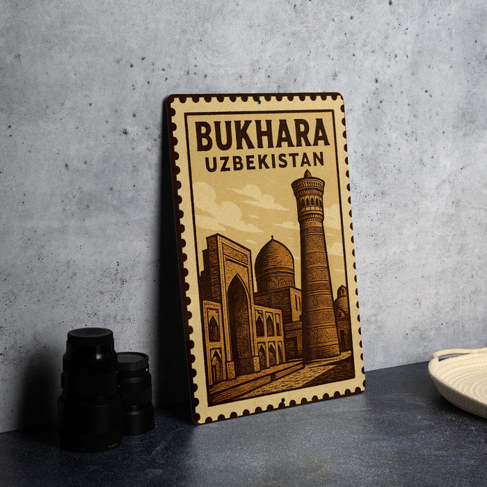 A wooden postcard with an illustration of a mosque and a tower, labeled as a souvenir from Bukhara, Uzbekistan.