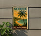 A vintage-style postage stamp depicting a tropical beach scene with palm trees and a sunset over the ocean, mounted on a wall.