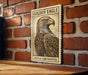 a wooden table with a framed poster of a golden eagle on it, mounted on a brick wall.
