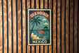 A vintage-style metal sign with a tropical beach scene and a flamingo, mounted on a wooden wall.