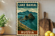 A vintage-style metal sign with a landscape depicting Lake Baikal, a famous landmark in Russia, is displayed on a shelf next to a wooden cutting board and some potted plants.
