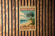 A vintage-style metal sign with the text "FRASER ISLAND AUSTRALIA" is displayed on a wooden wall.