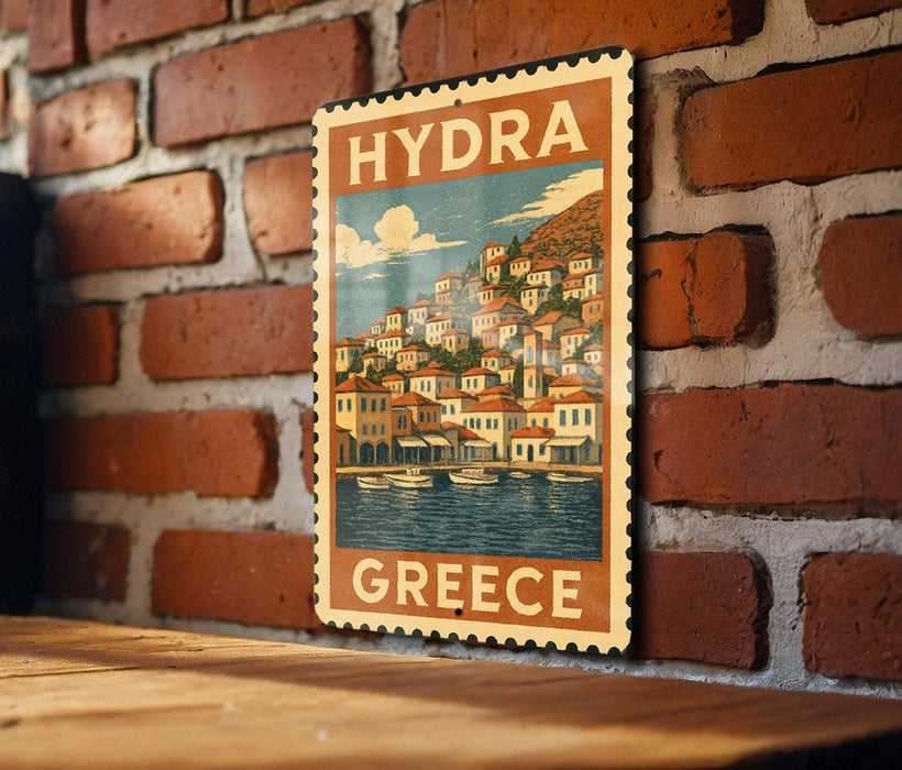 A vintage-style poster of a Greek island, featuring a coastal town with houses and boats, is displayed on a brick wall.