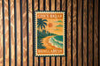 A vintage-style poster advertising " Cox's Bazar Bangladesh" is displayed on a wooden wall.