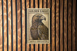 A framed image of a golden eagle is displayed on a wooden wall.