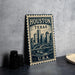 A metal sign with the text "HOUSTON TEXAS U.S.A." printed on it, featuring an illustration of a city skyline.