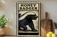 a vintage-style metal sign with a black and white illustration of a honey badger, placed on a wooden surface next to a wooden cutting board and some lemons.