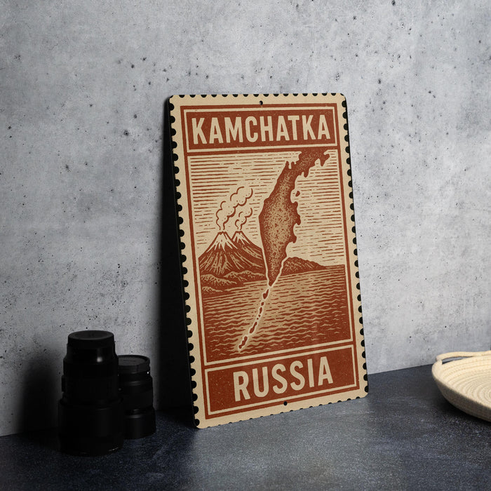 A wooden postcard with a map of Kamchatka, Russia, featuring a mountain and a body of water.