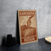 A wooden postcard with a map of Kamchatka, Russia, featuring a mountain and a body of water.
