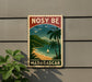 A vintage-style sign with a tropical beach scene and palm trees, featuring a sailboat in the water, mounted on a wall.