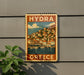 A vintage-style metal sign with the text "HYDRA GREECE" and an illustration of a coastal town with boats on the water.