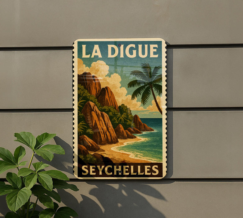 A vintage-style poster of the island of La Digue, featuring a tropical beach scene with palm trees and rocky cliffs, is displayed on a wall.