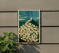 A vintage-style poster of a Greek island with a mountain and buildings, mounted on a wall.