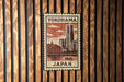 A postage stamp featuring a cityscape of Yokohama, Japan, with a ferris wheel and other buildings in the background.
