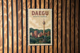 A vintage-style postage stamp depicting the Daegu, South Korea, skyline, with a traditional Korean temple in the foreground.