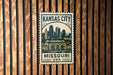 A metal sign with the text "KANSAS CITY MISSOURI USA" and an illustration of a city skyline.