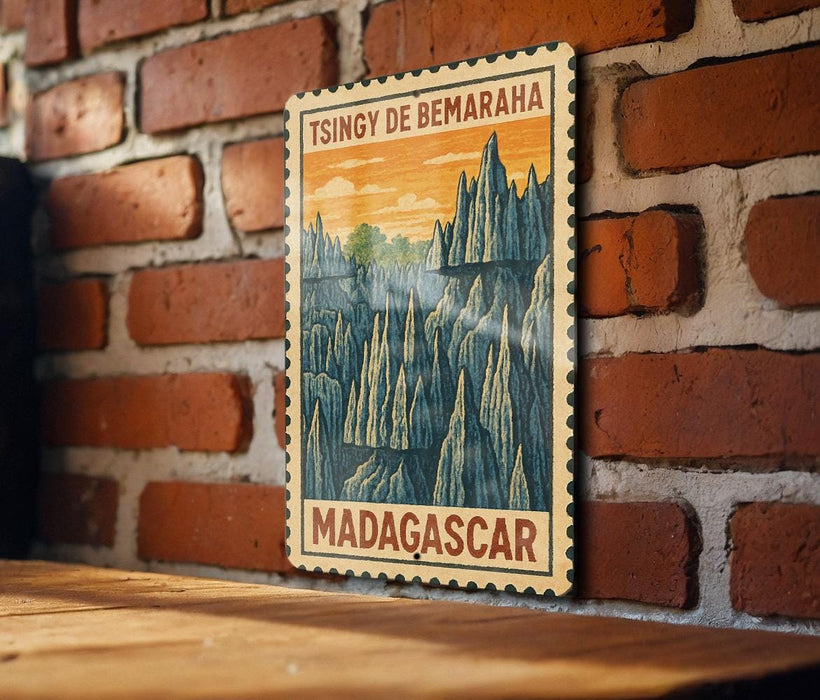 A vintage-style postage stamp depicting a mountainous landscape with the text "TSINGY DE BEMARHA MADAGASCAR" printed on it, hanging on a brick wall.