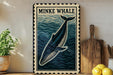 a framed illustration of a Minke whale on a wall, with a wooden cutting board and a potted plant to the side.