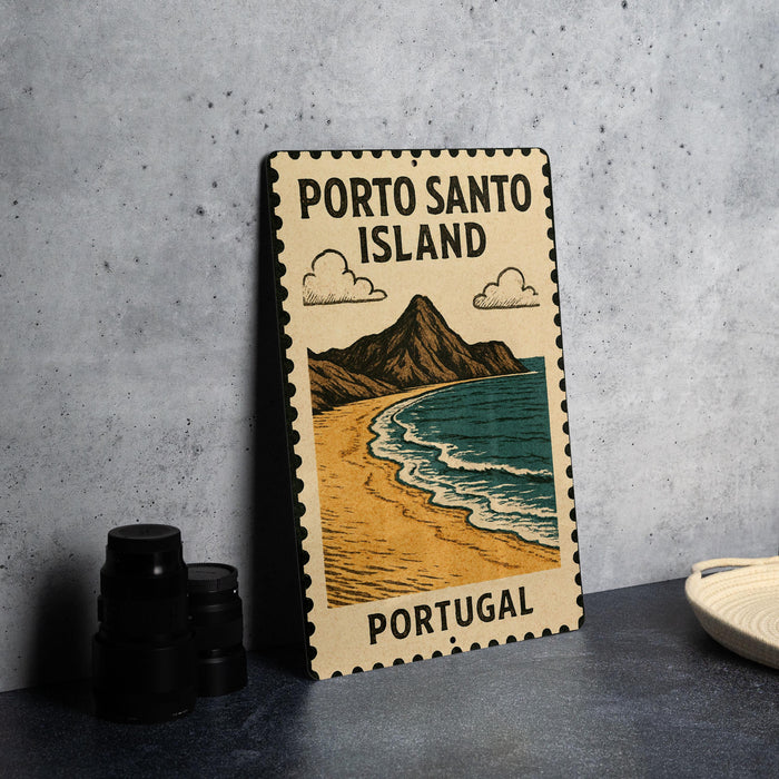 A vintage-style metal sign with the text "PORTO SANTO ISLAND" and an illustration of a beach and mountains, placed on a gray countertop next to some black camera lenses.