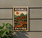 A vintage-style postage stamp depicting a cityscape with a prominent dome, surrounded by trees and buildings, with the text "KIGALI RWANDA" prominently displayed.