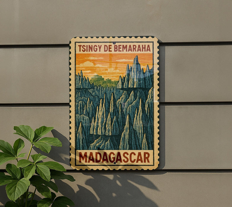 A vintage-style postage stamp depicting a mountainous landscape with the text "TSINGY DE BEMARAH" and "MADAGASCAR" printed on it, hanging on a wall next to a plant.