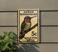 A wooden sign with a hummingbird illustration and text, mounted on a wall next to a plant.
