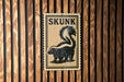 A sign with the word "SKUNK" and a graphic of a skunk is displayed on a wooden wall.
