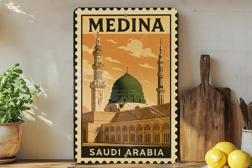 A vintage-style metal stamp depicting the Medina, the largest city in Saudi Arabia, with the text "SAUDI ARABIA" printed on it. The stamp is displayed on a shelf, surrounded by various kitchen items such as a wooden cutting board, a lemon, and a potted plant.